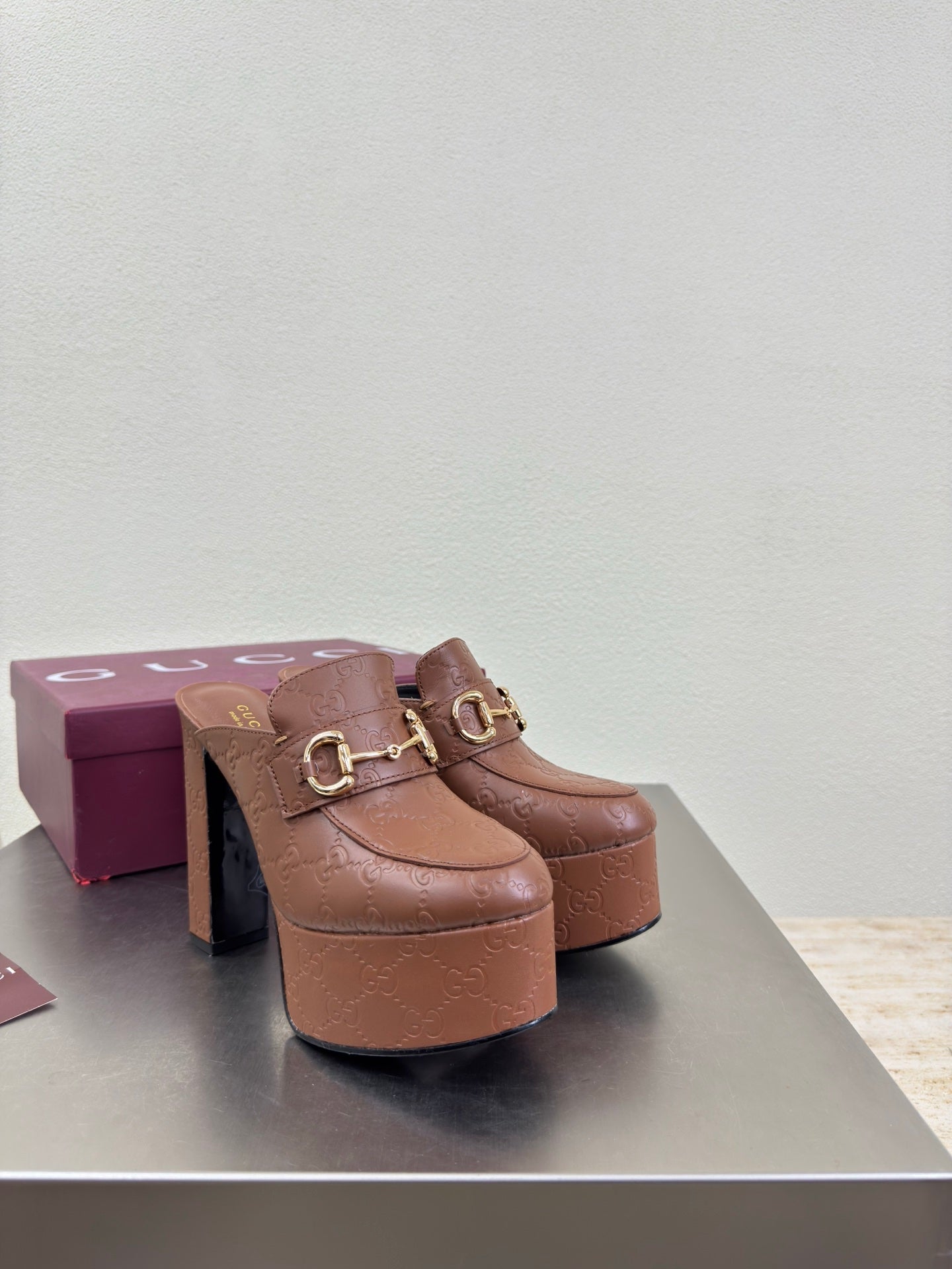 Brown Gucci platform mule with gold buckle detail and sculpted block heel, single shoe