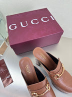 Brown Gucci logo platform mules with gold horsebit buckle and dark interior, two shoes