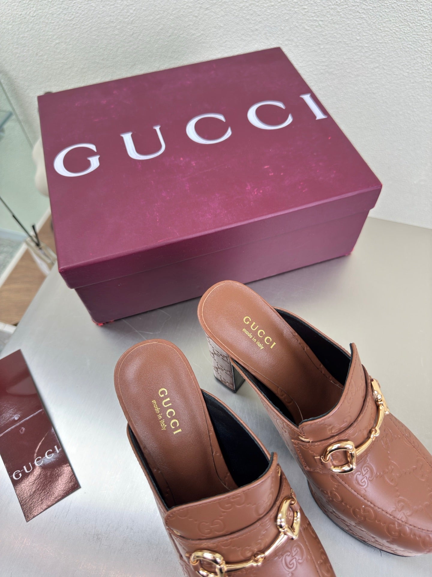 Brown Gucci logo platform mules with gold horsebit buckle and dark interior, two shoes