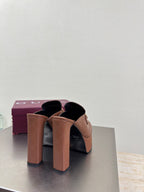 Brown Gucci platform mules with tall block heels and logo texture, rear angle