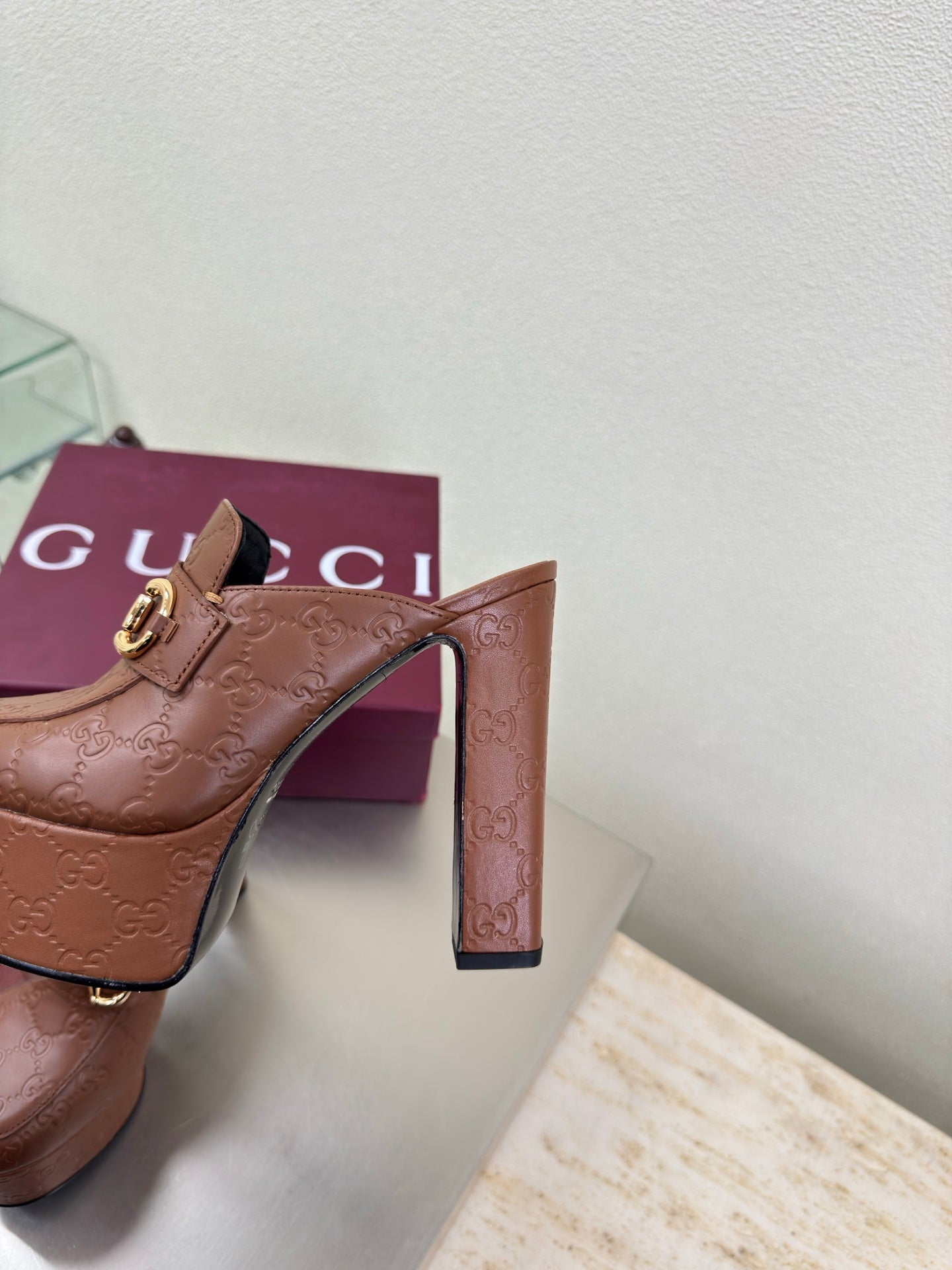 Brown Gucci platform mule close-up of front strap and tall heel, gold buckle hardware