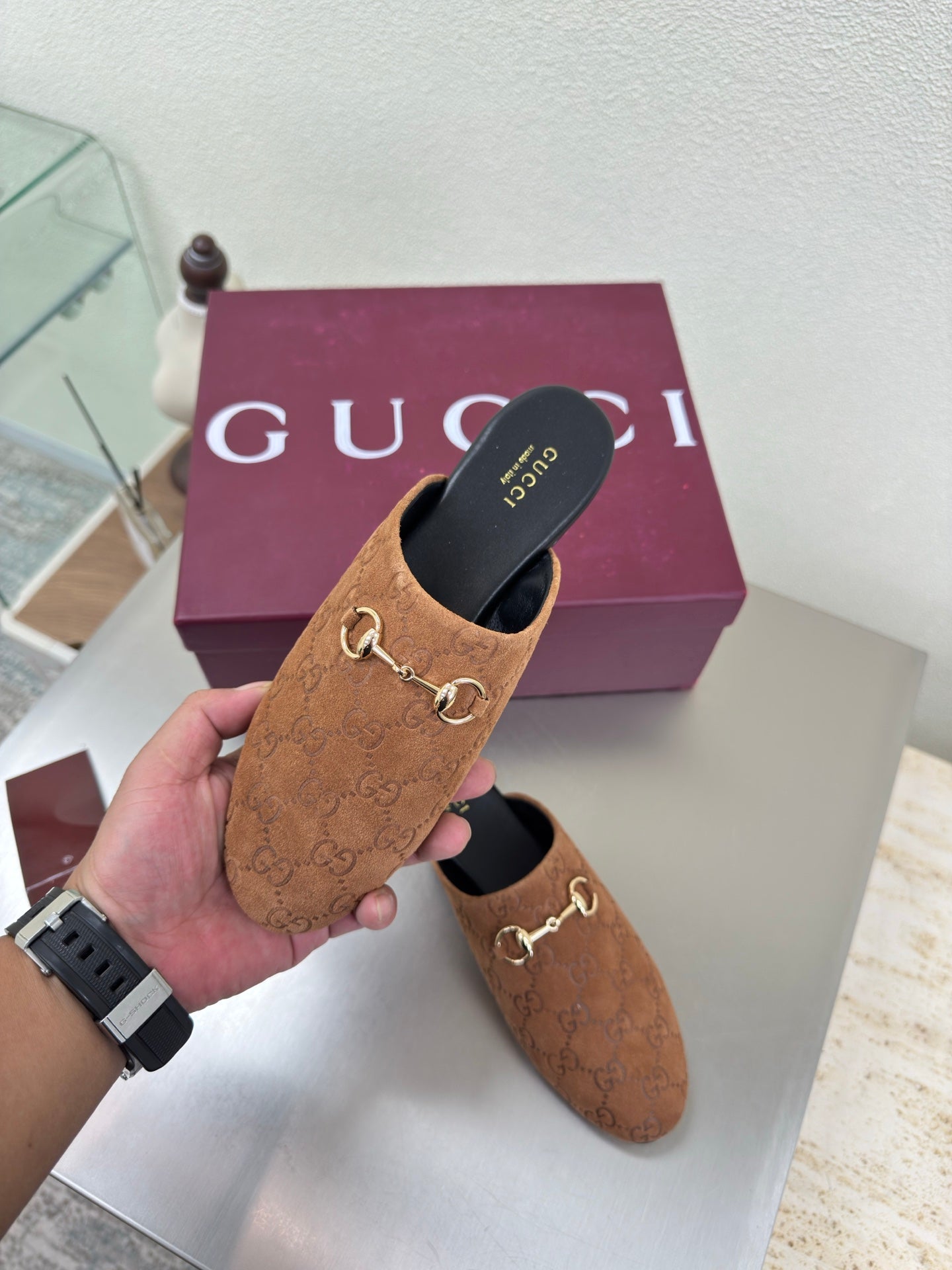 Women's brown monogram loafer held up; gold chain bit and black insole
