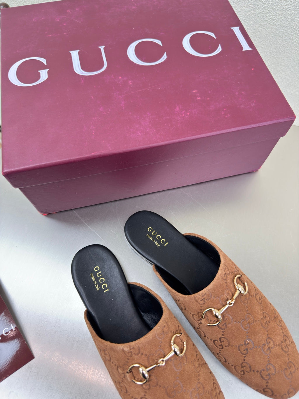 Pair of women's brown loafers with gold chain detail; black insoles labeled Gucci