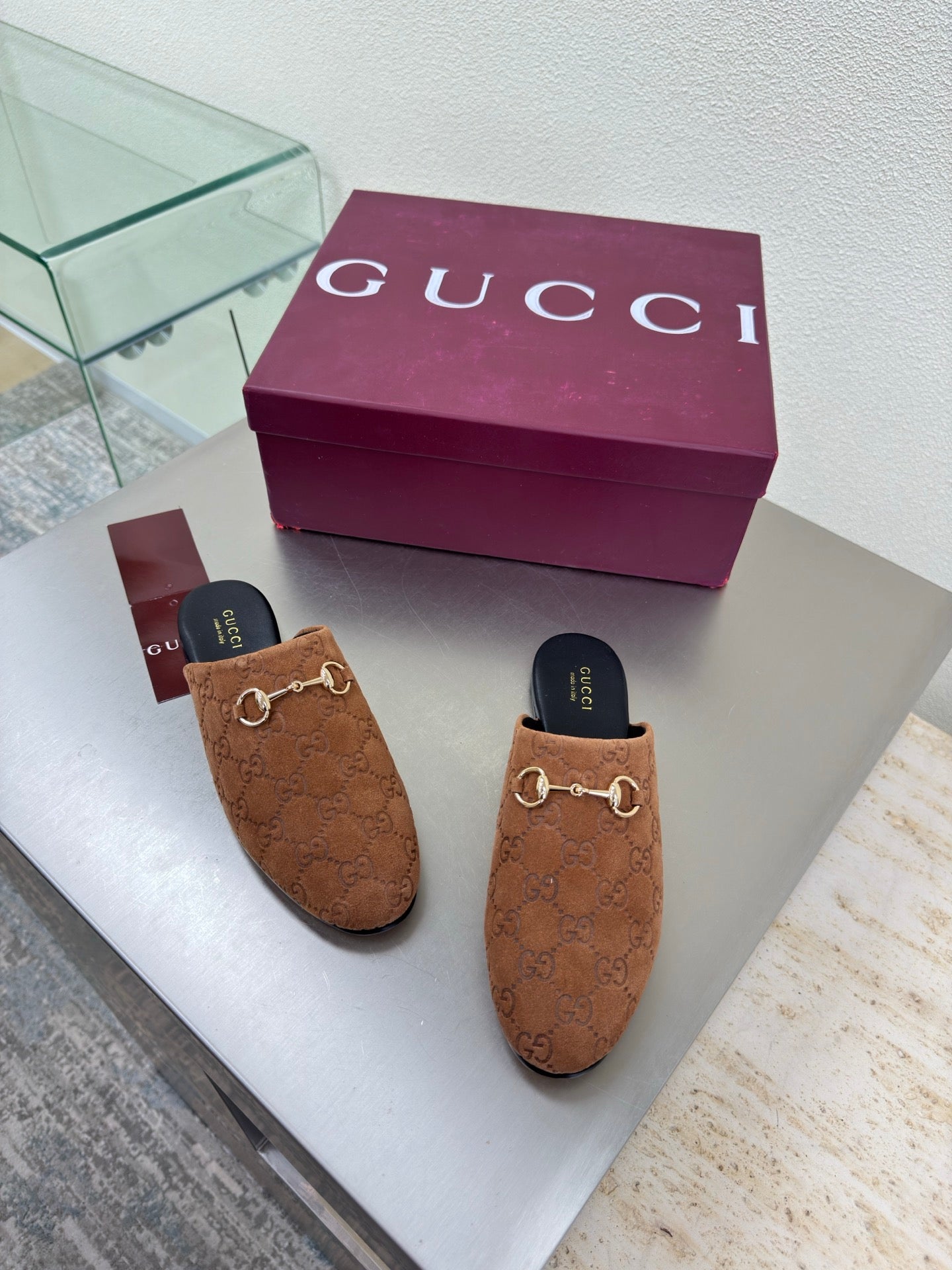 Women's brown monogram loafers with gold chain bit on display with purple box