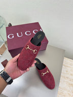 Gucci women's burgundy GG-pattern mule shoes with gold horsebit, held above box