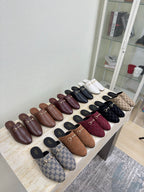 Gucci women's mule shoes assortment on display table, GG patterns in multiple colors