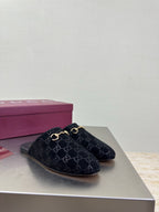 Black Gucci mule shoes with GG logo print and gold horsebit detail, side view