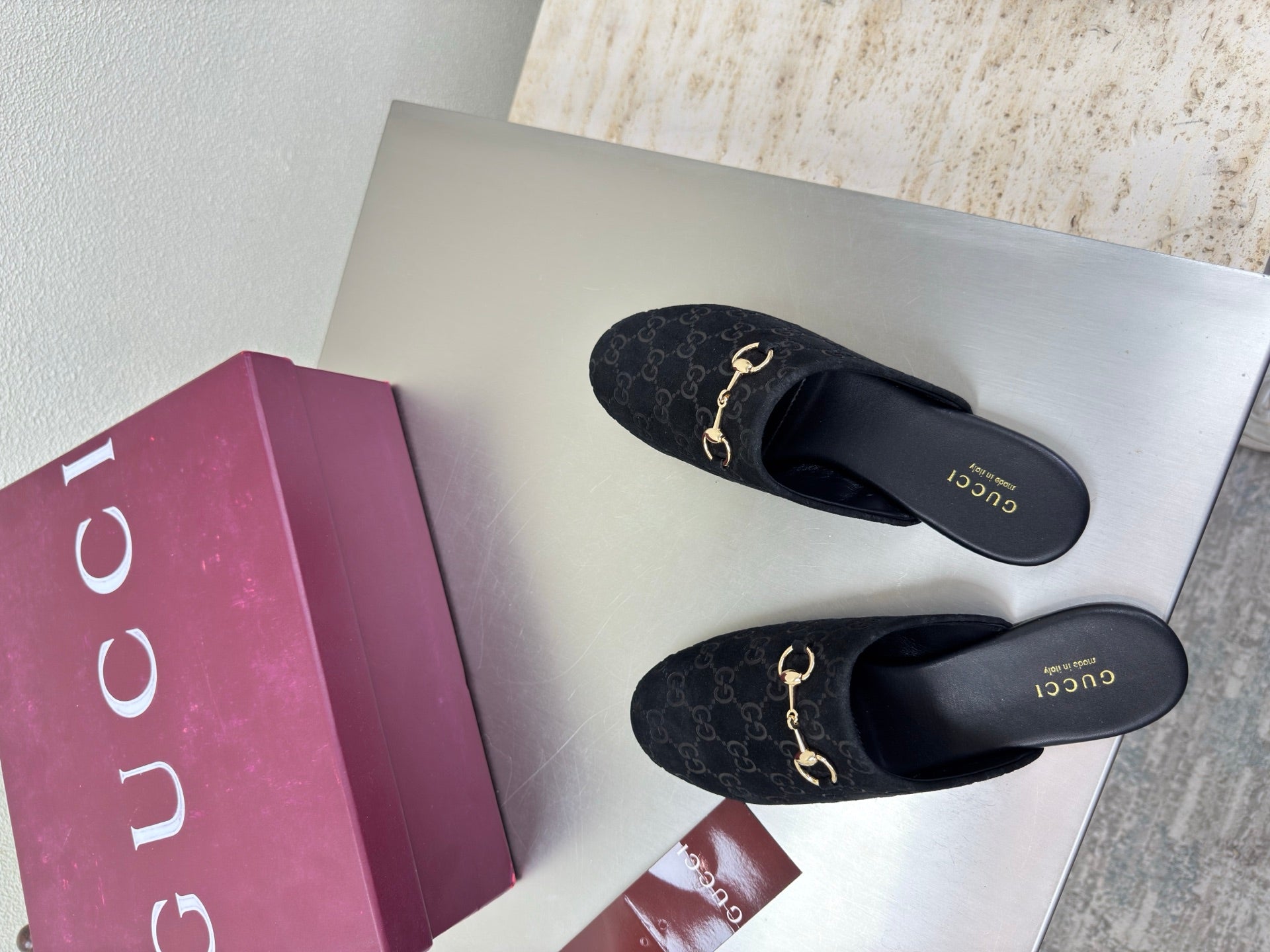 Black Gucci mules with GG logo print and gold horsebit detail, top view