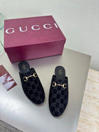Black Gucci mules with GG logo print and gold horsebit detail, with purple box