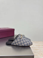 Women’s Gucci GG-pattern slide mules with black sole, side view on display
