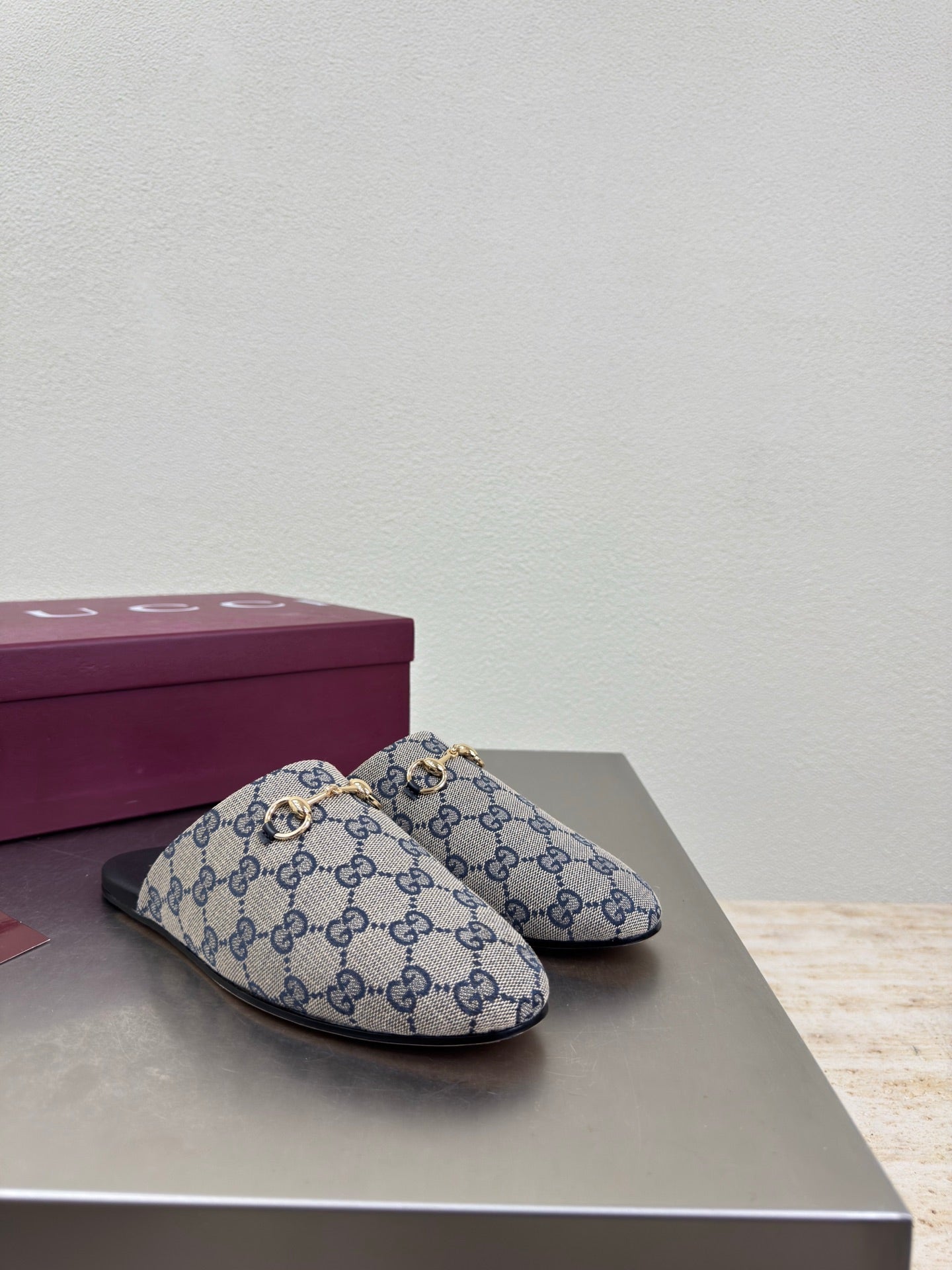 Women’s Gucci GG-pattern slide mules, single pair on display with black outsole