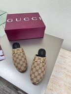 Gucci women’s GG-pattern slip-on loafers with black soles, shown as a pair