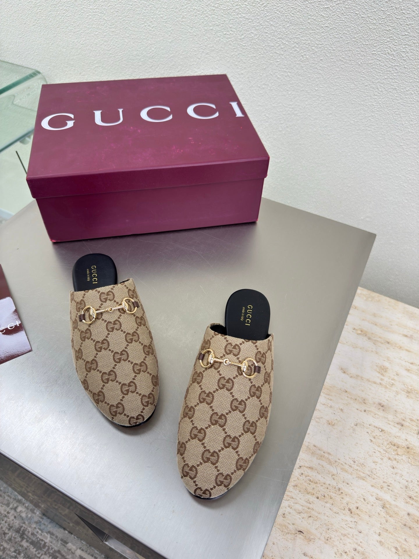 Gucci women’s GG-pattern slip-on loafers with black soles, shown as a pair
