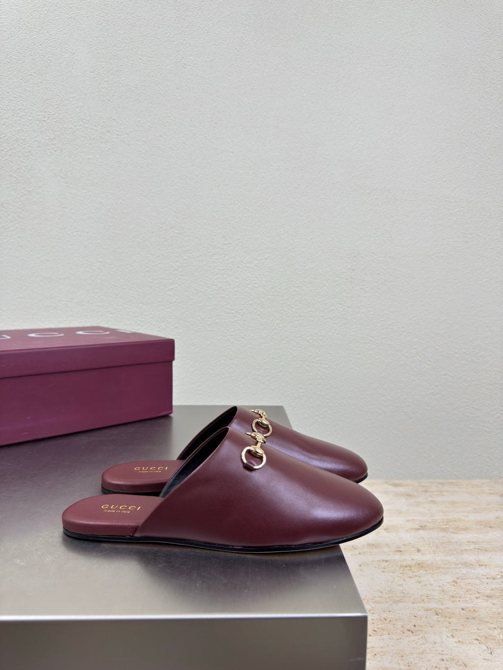 Burgundy leather slide mule with gold horsebit hardware and open heel opening