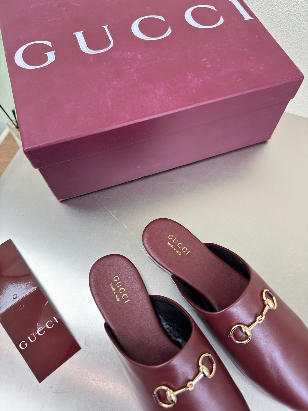 Two burgundy leather mules with gold horsebit hardware and Gucci logo insoles