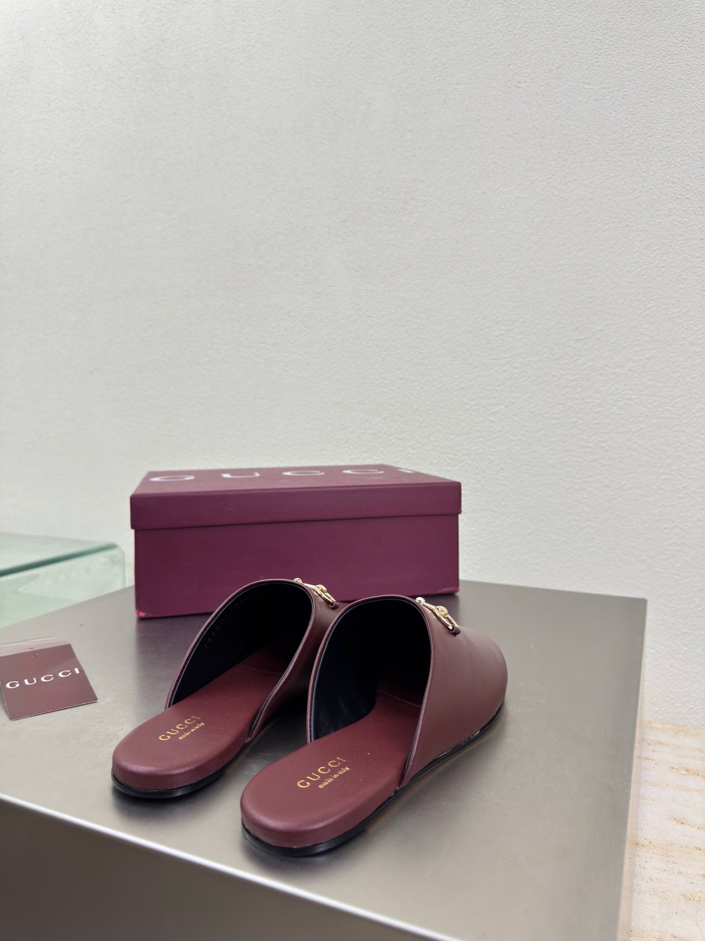 Burgundy leather mules with gold horsebit on the vamp, shown side by side