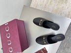 Gucci black leather mules with gold horsebit detail, shown on white display surface