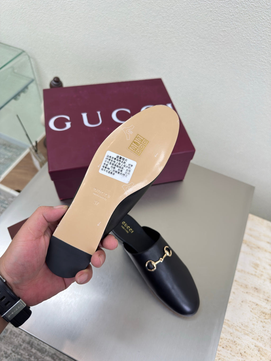 Gucci black leather mule showing tan sole and gold horsebit detail, slip-on
