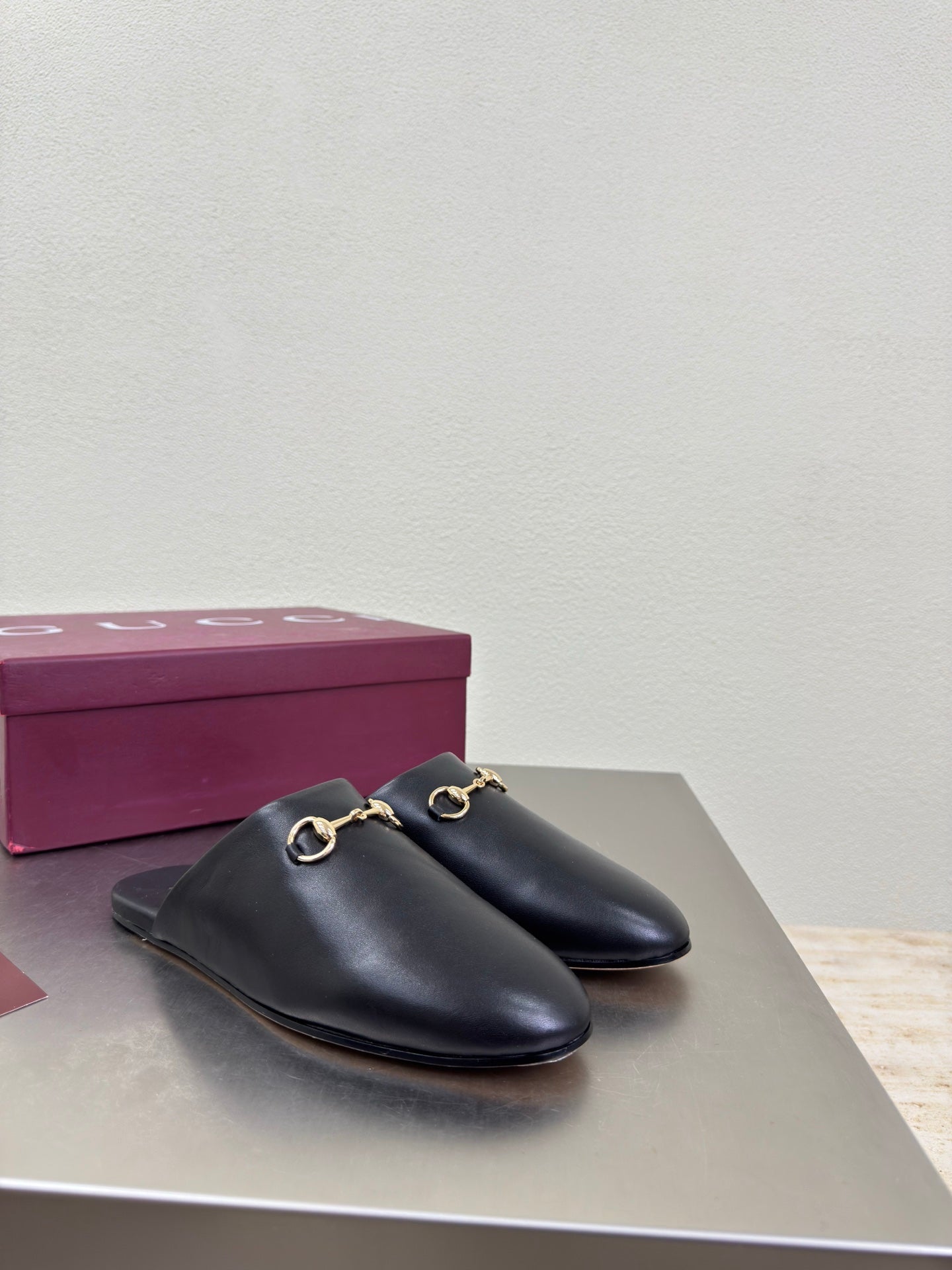 Gucci black leather mules with gold horsebit detail on a light base, rounded toe