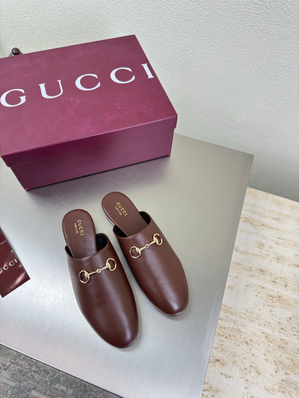 Brown Gucci leather mules with gold horsebit hardware, slip-on design