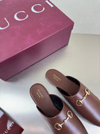 Brown Gucci leather mules, rounded toe and gold bit detail on the vamp