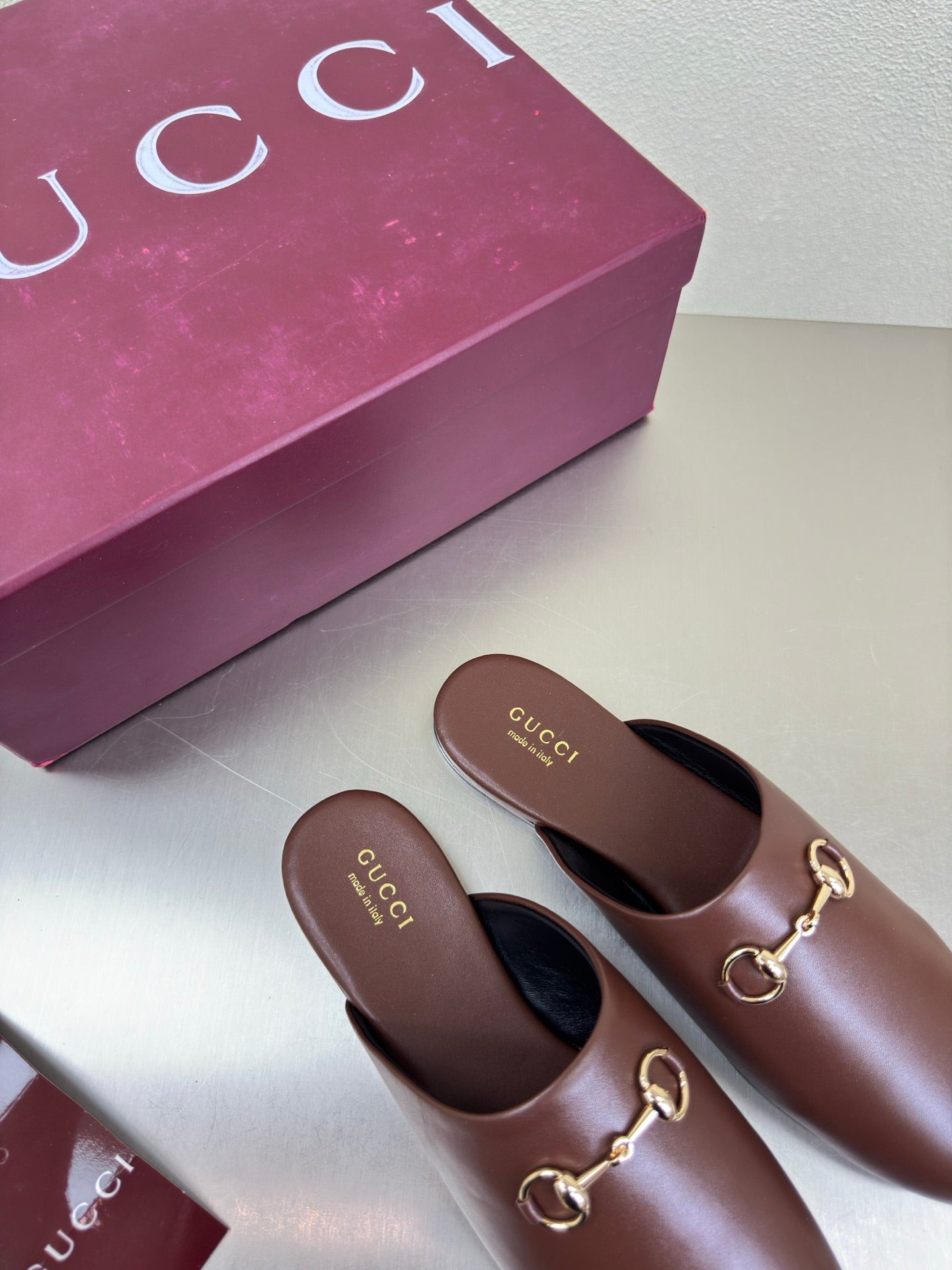 Brown Gucci leather mules, rounded toe and gold bit detail on the vamp