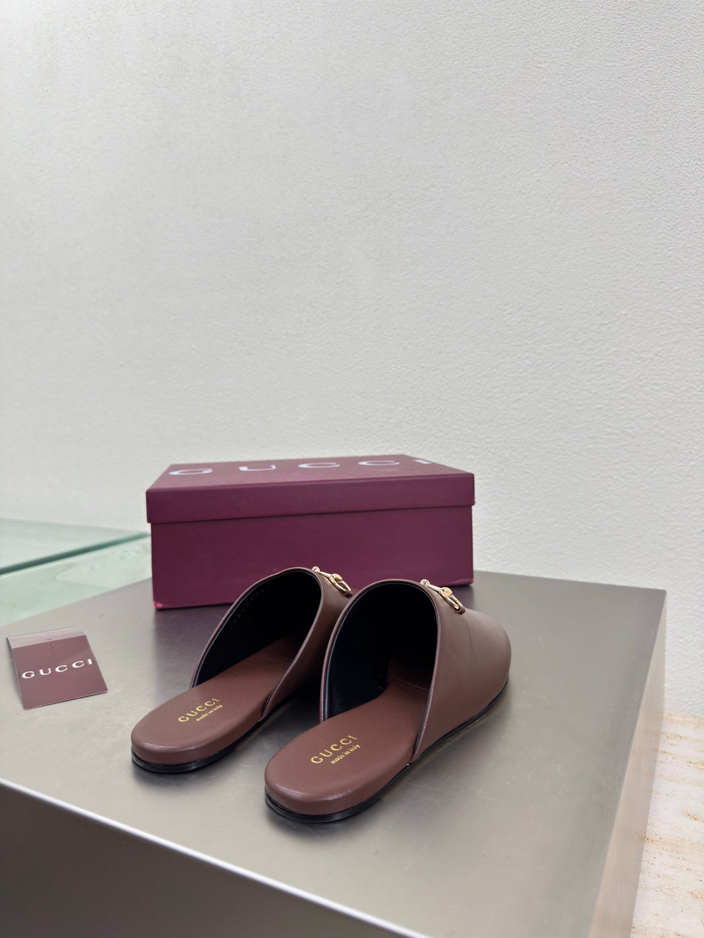 Brown Gucci leather mules on display with gold horsebit detail