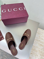 Pair of brown Gucci leather mules with gold horsebit hardware on vamp