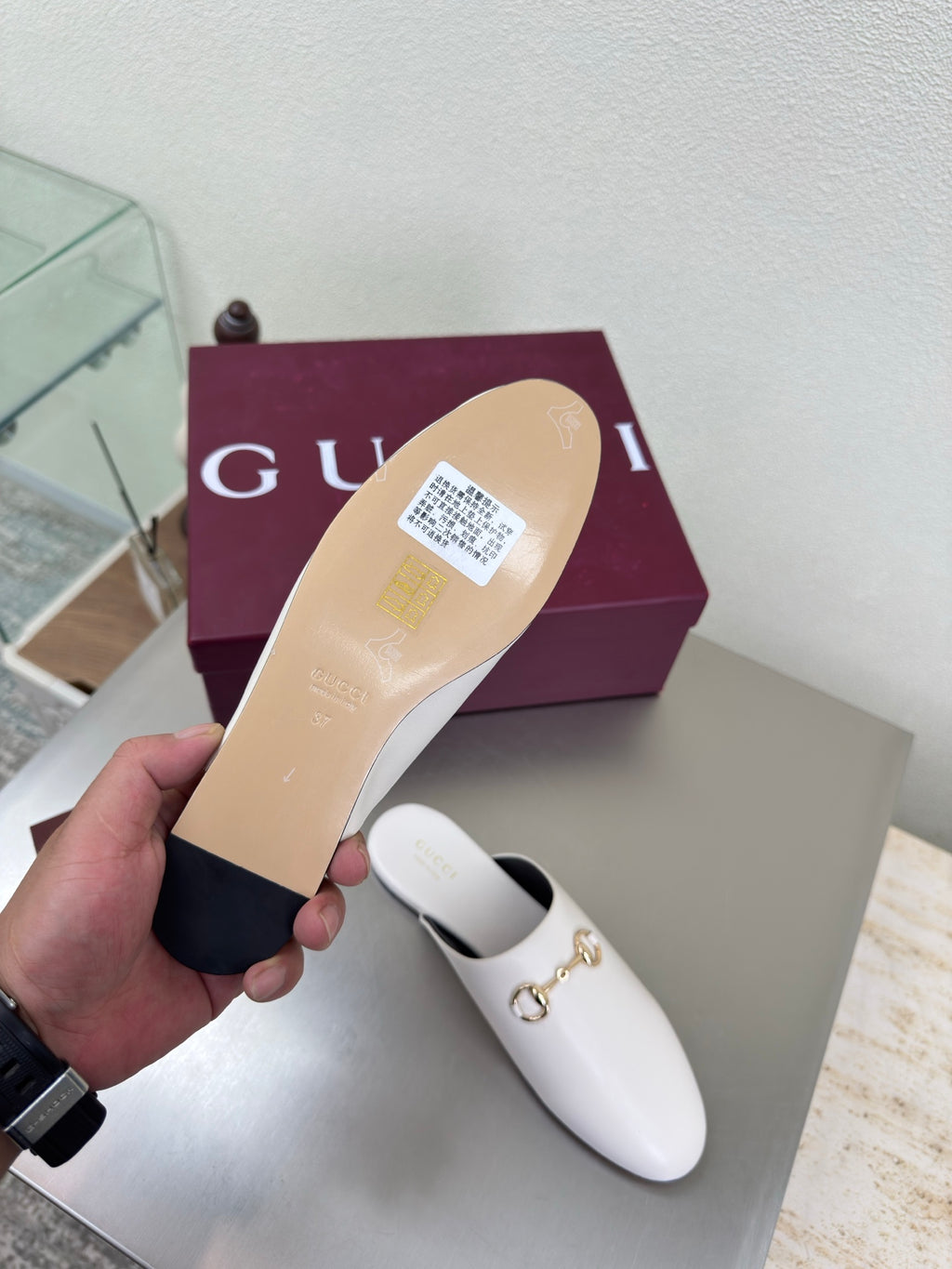White mule shoe sole with label, underside view held in hand