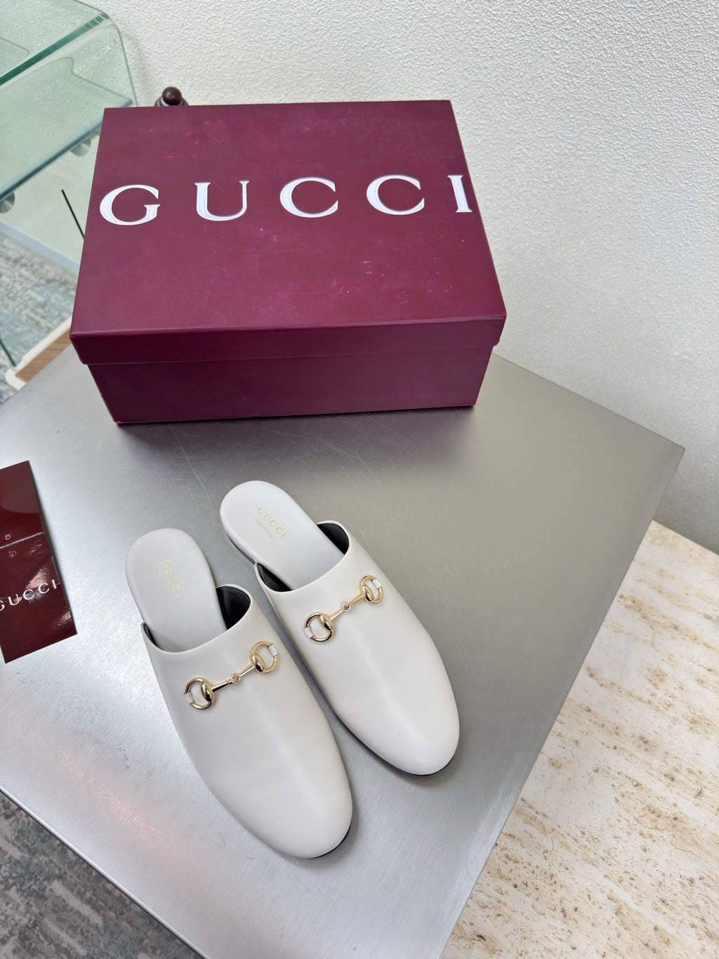 White mule shoes with gold horsebit detail and black insole, pair on box