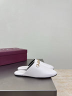White mule slide with gold horsebit detail, single shoe on display