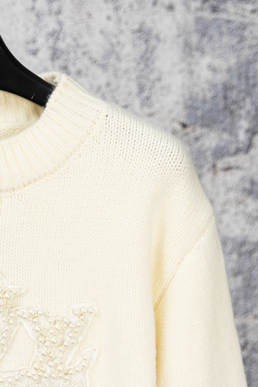 Ivory knit sweater shoulder with beaded emblem detail