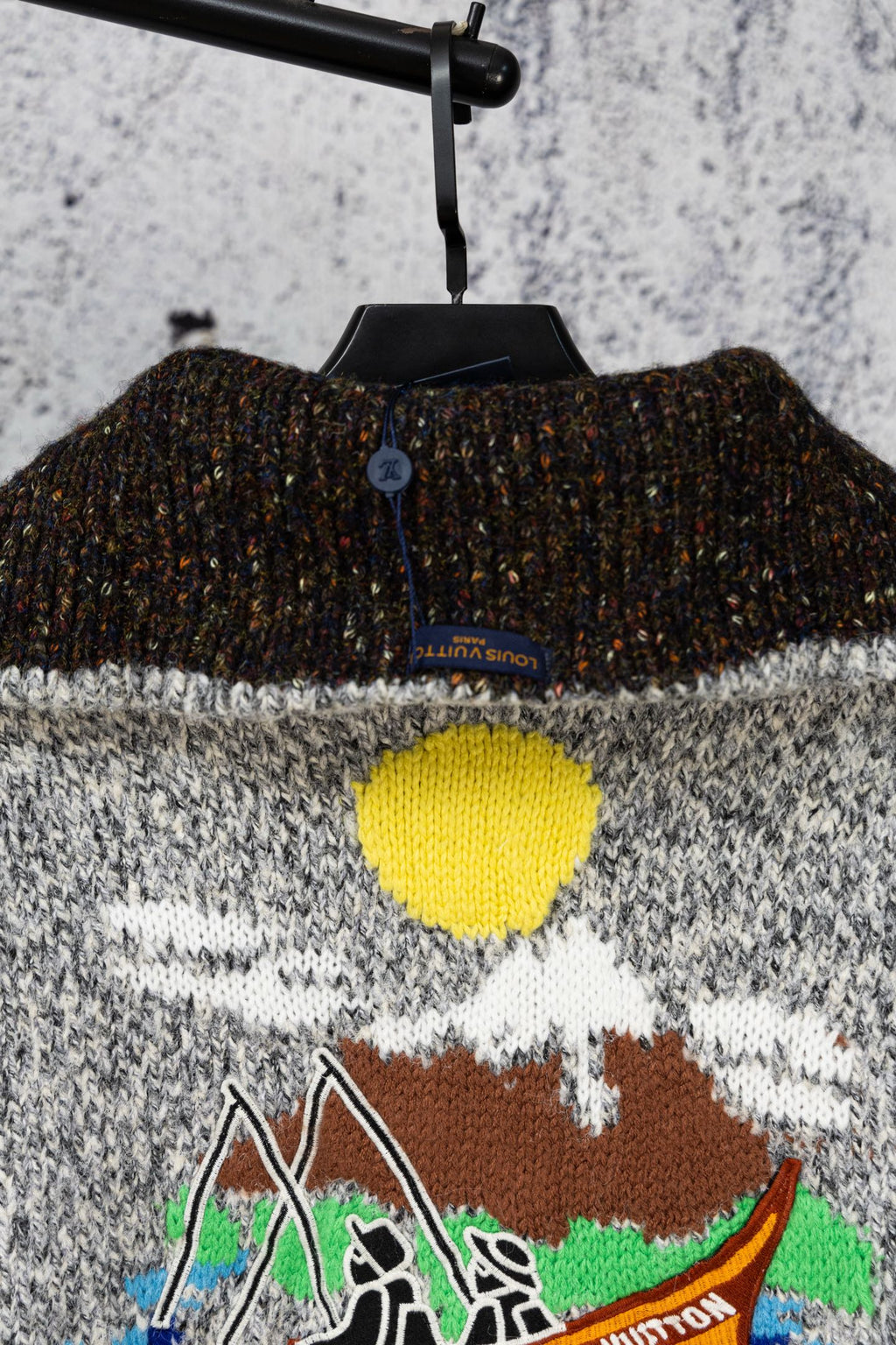 Grey knit sweater back with black ribbed collar band and colorful chest graphic