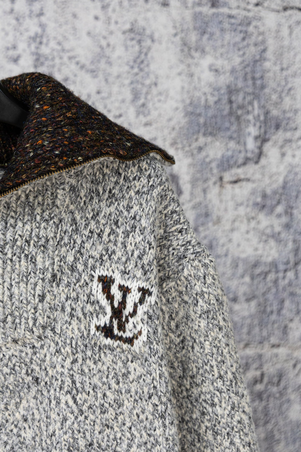 Knit sweater chest detail with dark speckled collar and small emblem
