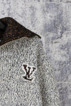 Knit sweater chest detail with dark speckled collar and small emblem