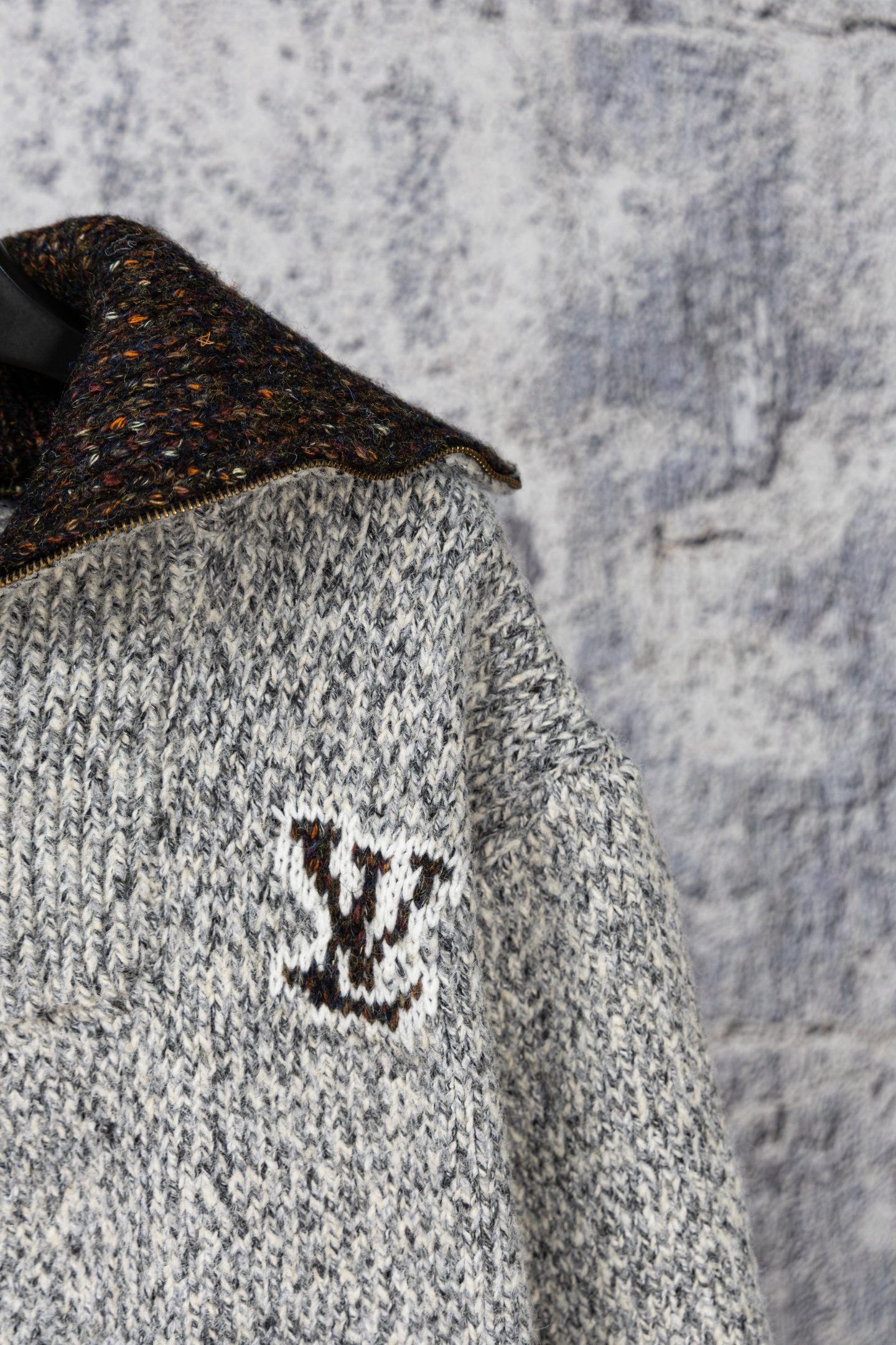 Knit sweater chest detail with dark speckled collar and small emblem