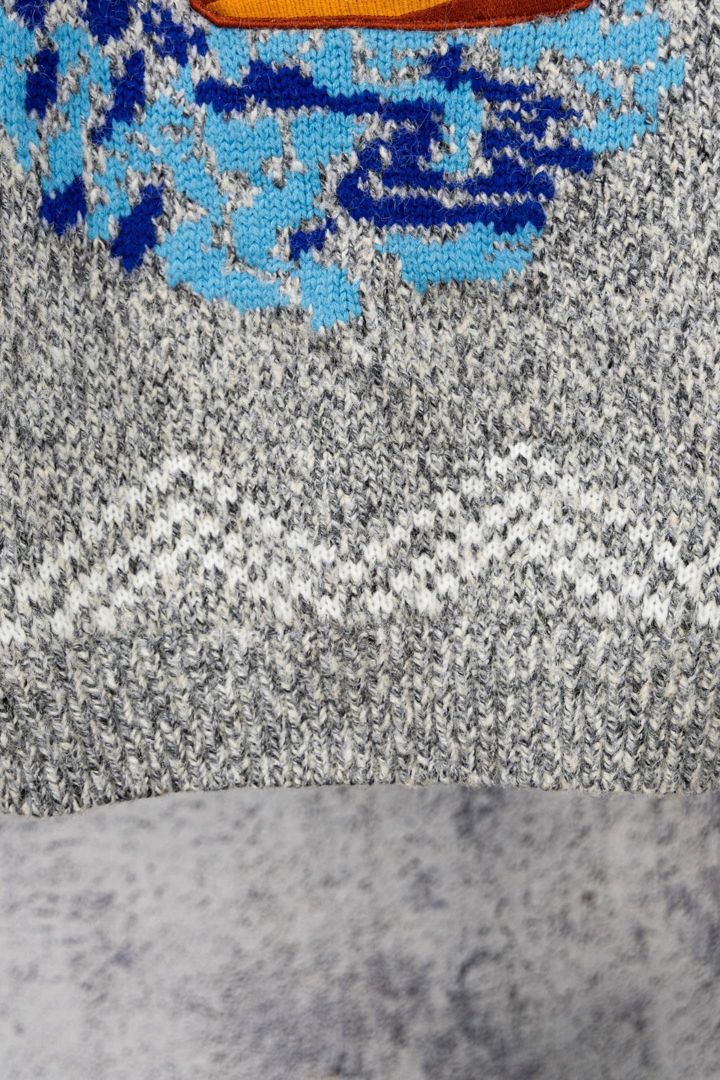 Grey knit sweater with blue and multicolor chest graphic detail
