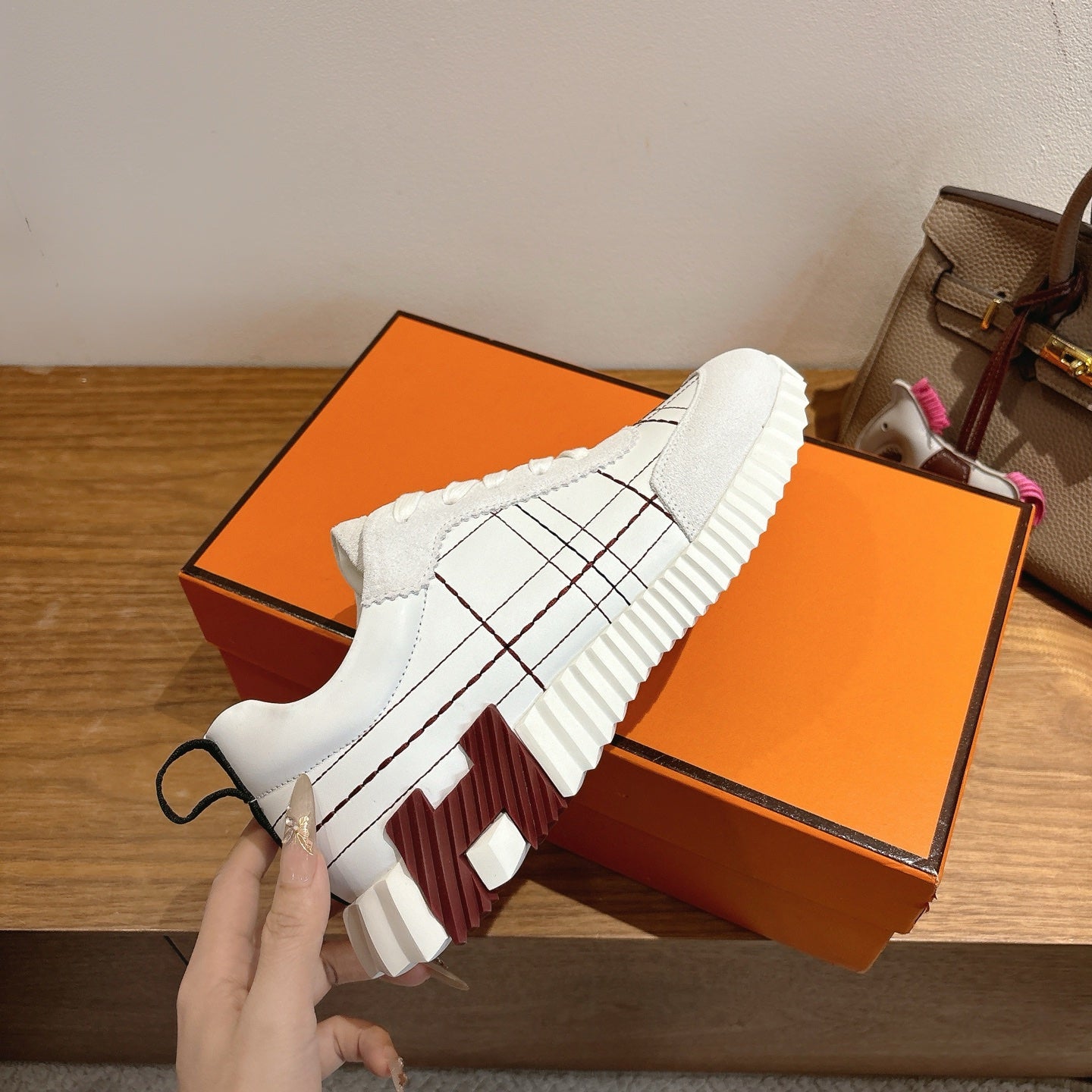 Hermes unisex white sneakers, lace-up with black grid stitching and thick rubber sole.