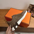 Gray sneaker on orange box, showing striped sole tread and lace-up upper