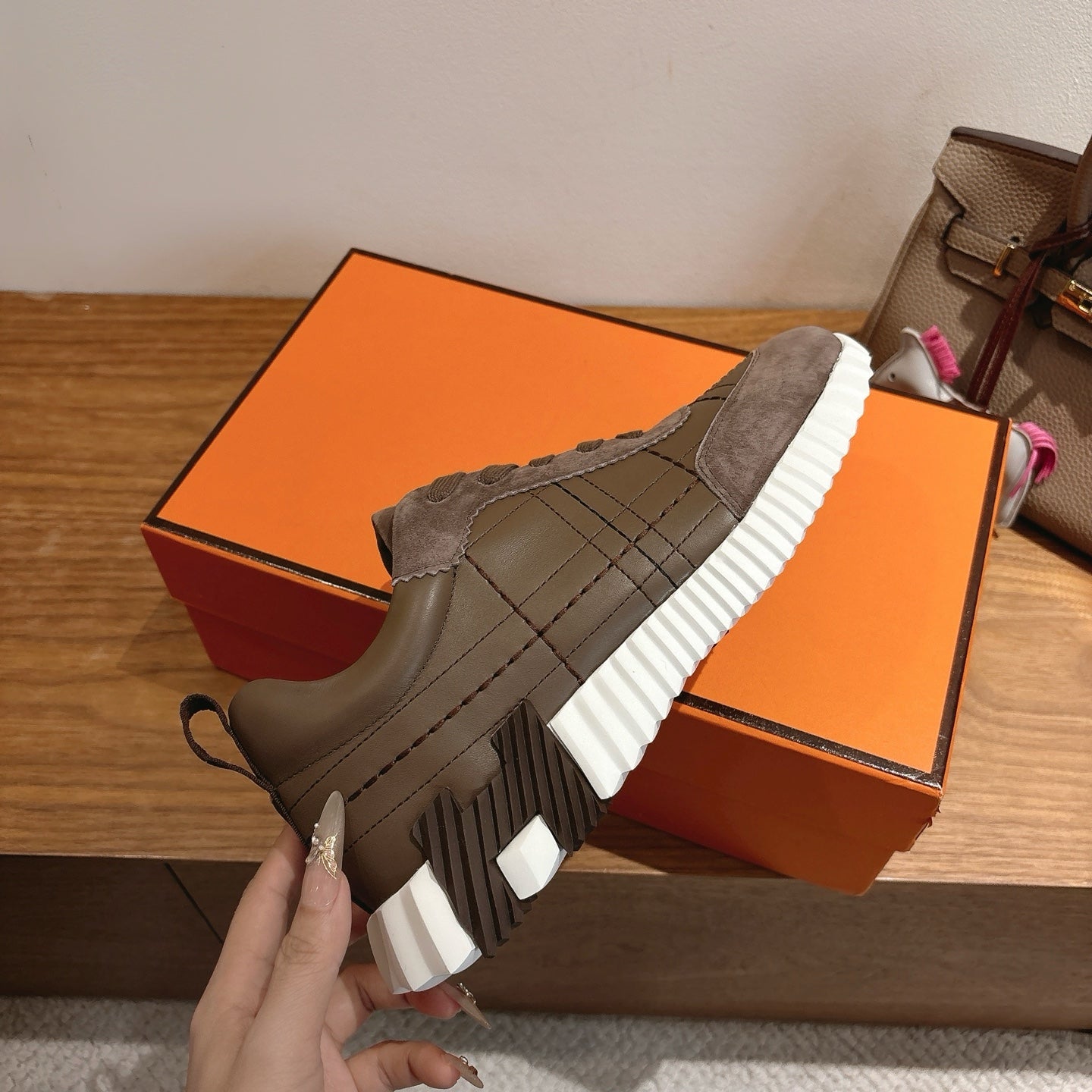 Gray sneaker on orange box, showing striped sole tread and lace-up upper
