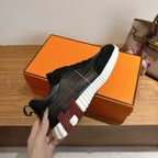 Black lace-up sneaker held up, silver side panel and striped chunky sole