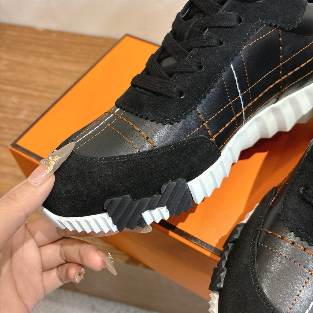 Black lace-up sneaker close-up with textured sole, stitching, and silver panel