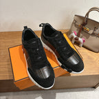 Black lace-up sneakers on orange box, silver panel accents and white sole