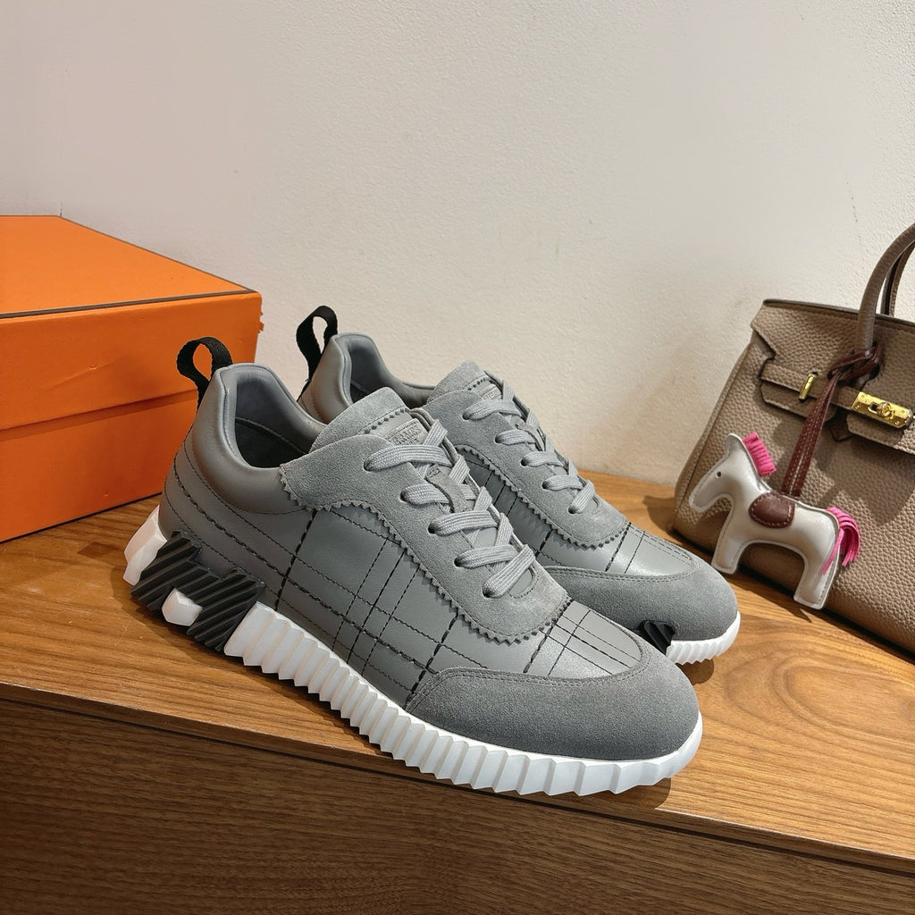Gray lace-up sneakers with stitched grid panels and chunky white sole.