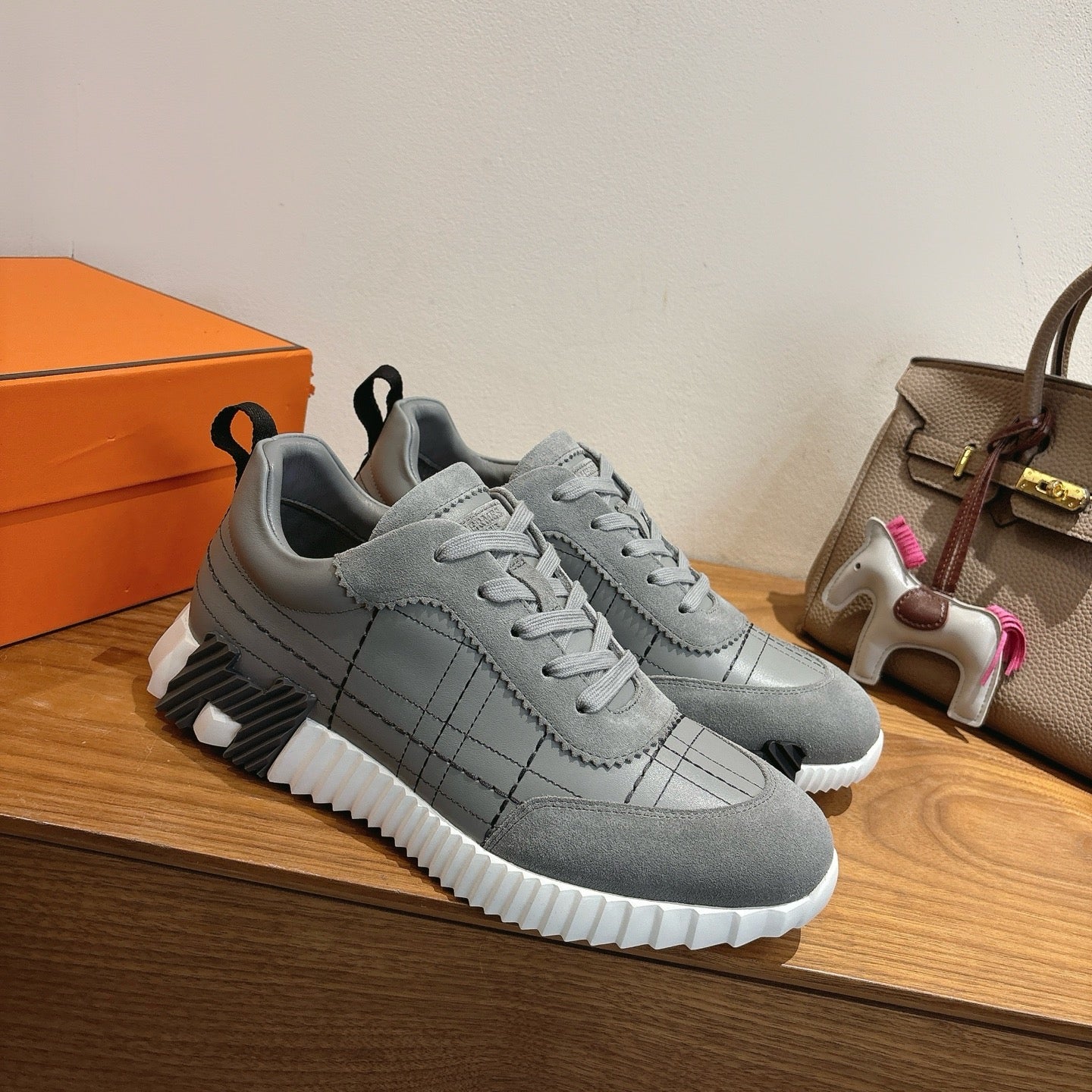 Gray lace-up sneakers with stitched grid panels and chunky white sole.