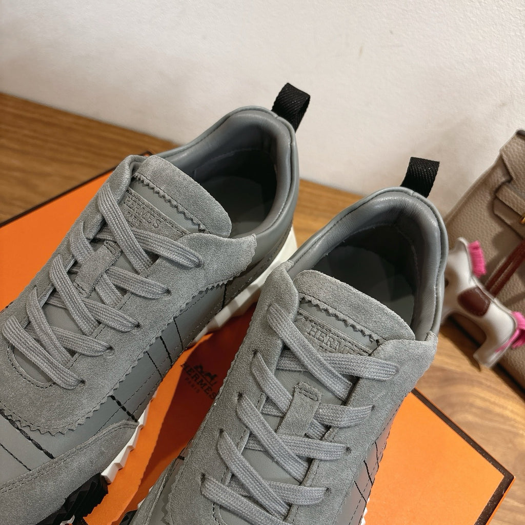 Gray suede sneakers close-up showing lace eyelets, stitching, and black heel tabs.