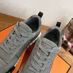Gray suede sneakers close-up showing lace eyelets, stitching, and black heel tabs.
