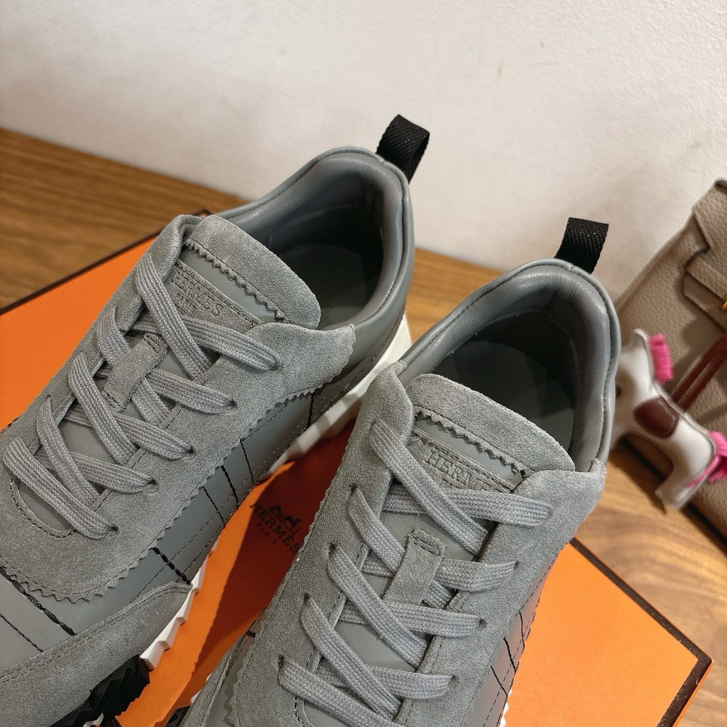 Gray suede sneakers close-up showing lace eyelets, stitching, and black heel tabs.