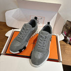 Gray lace-up sneakers in an open box, with black heel tabs and white rubber sole.