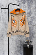 Beige knit zip-up sweater with orange hood, orange cuffs, and black geometric accents